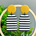 Black and white striped earrings with mustard yellow circular tops