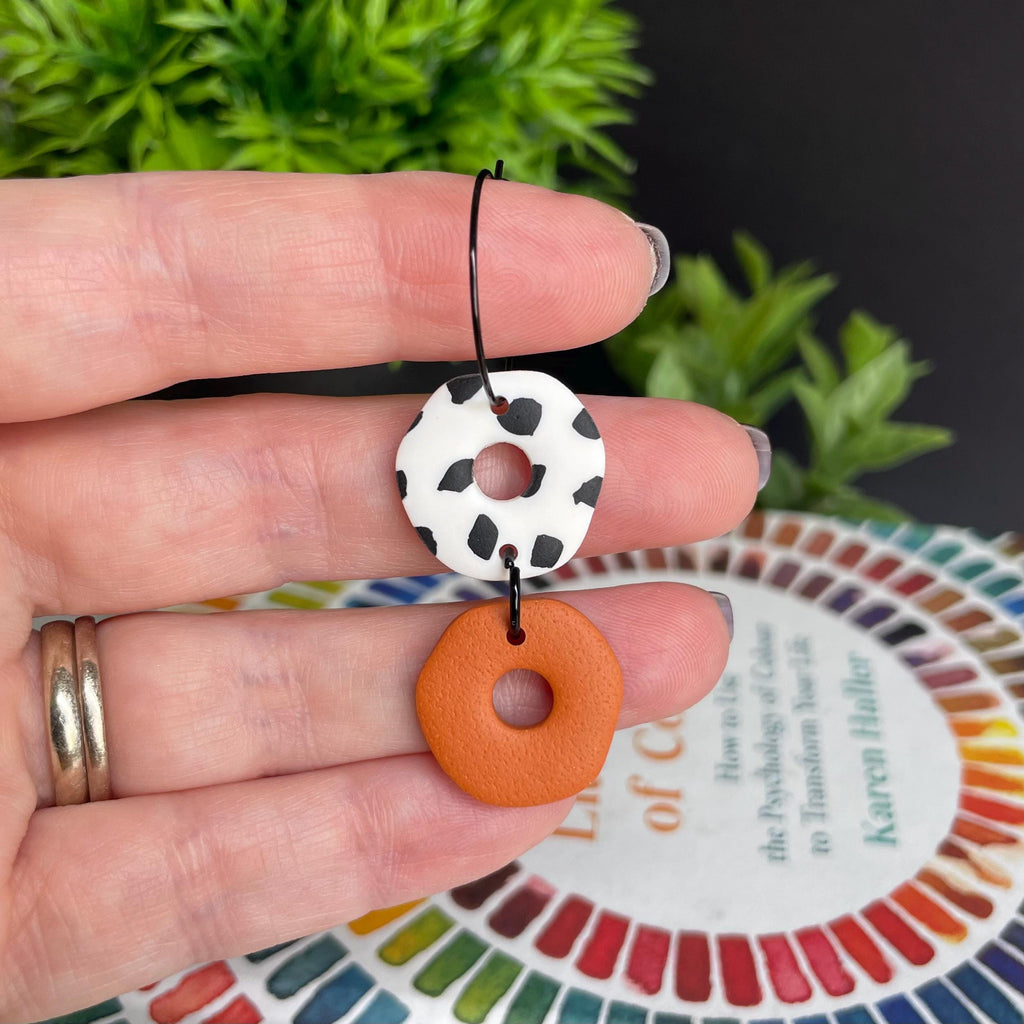 Hand holding a Burnt orange & Dalmatian print hoop earring