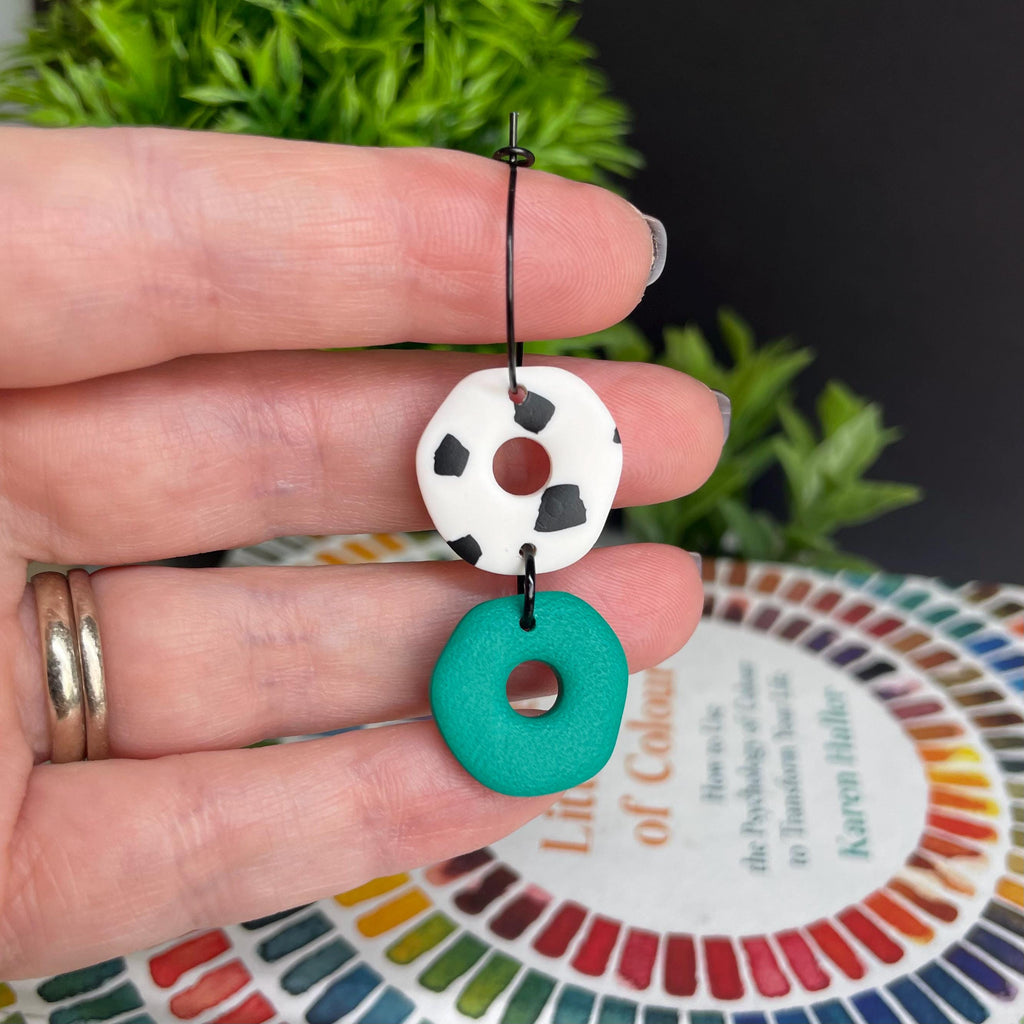 Hand holding a pair of Emerald Green Dalmatian print hoop earring