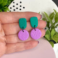Emerald Green & Lilac colour pop dangle earrings held in hand for size reference