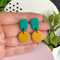 Emerald Green & Mustard Yellow colour pop dangle earrings held in hand for size reference