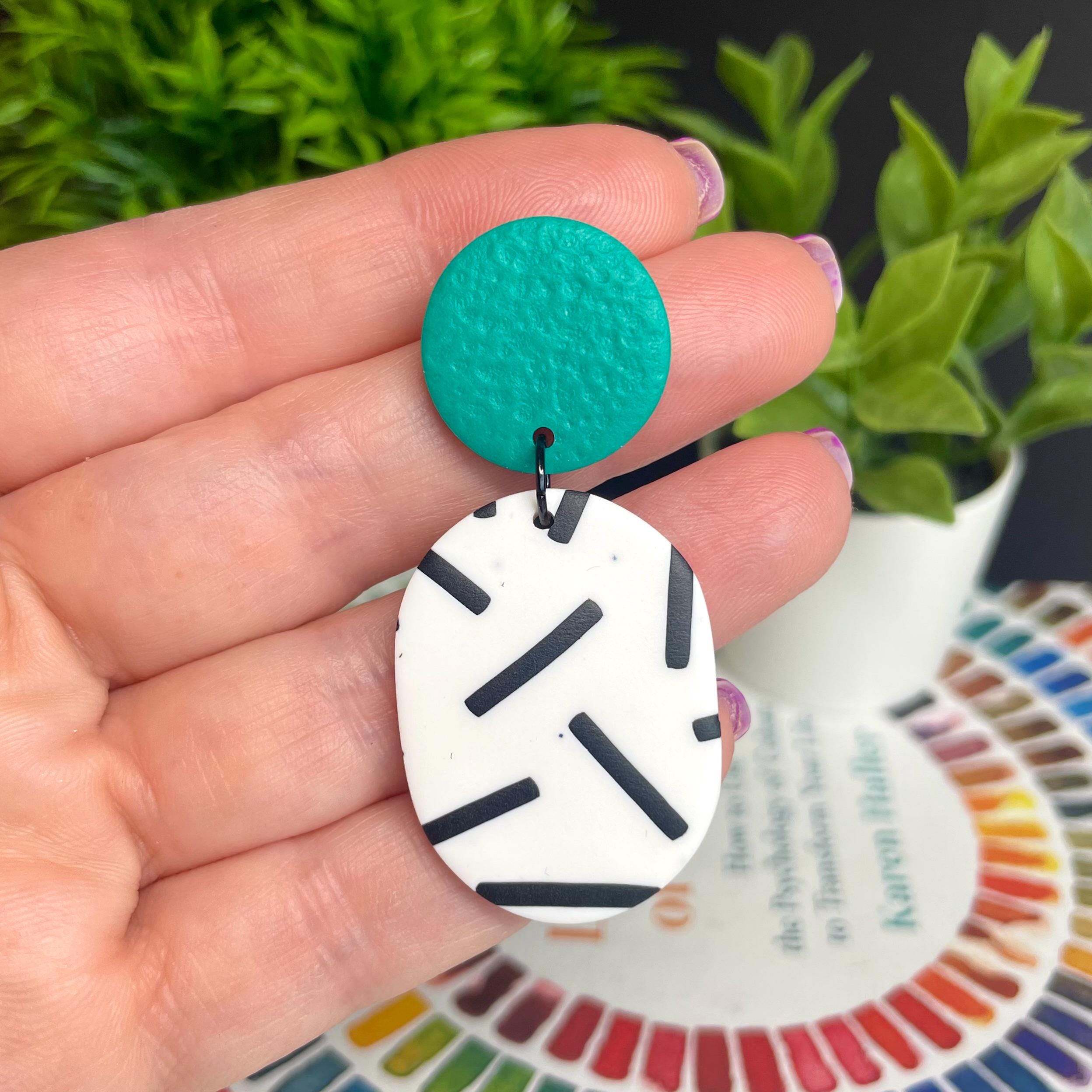 Hand holding an earring with emerald green tops & monochrome sprinkle oval bottom 