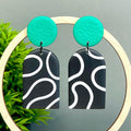 Black and white squiggle patterned earrings with emerald green circular tops 