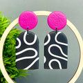 Black and white squiggle patterned dangle earrings with hot pink tops