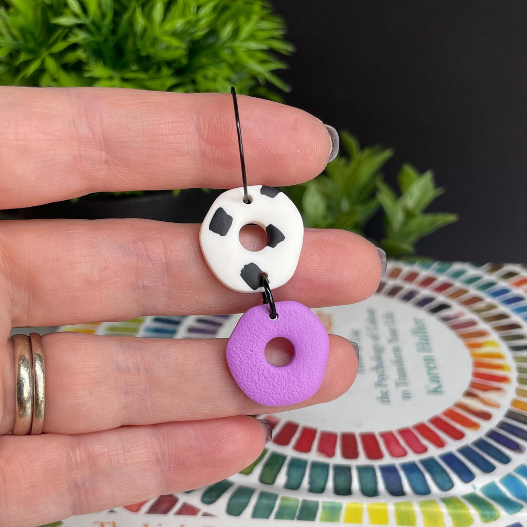 Hand holding a Lilac & Dalmatian print hoop earrings