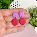 Lilac & Red colour pop dangle earrings held in hand for size reference