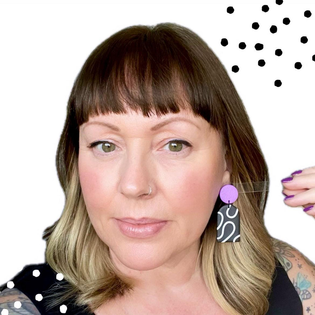 Try on picture of Kerry from Kay Jay Clay wearing the monochrome squiggle dangle earrings with the lilac top for size reference