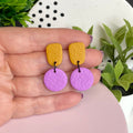 Mustard Yellow & Lilac colour pop dangle earrings held in hand for size reference