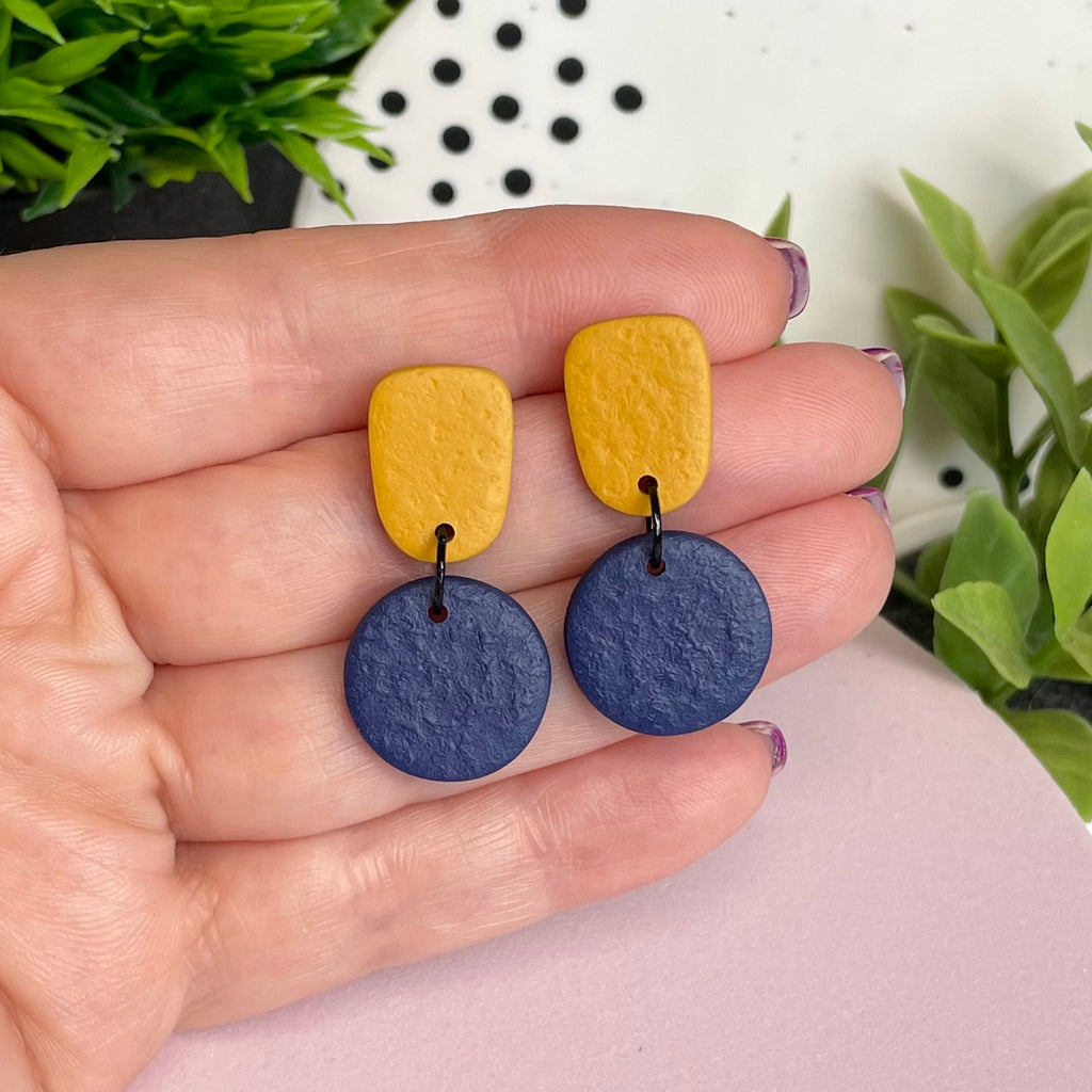 Mustard Yellow & Navy Blue colour pop dangle earrings held in hand for size reference