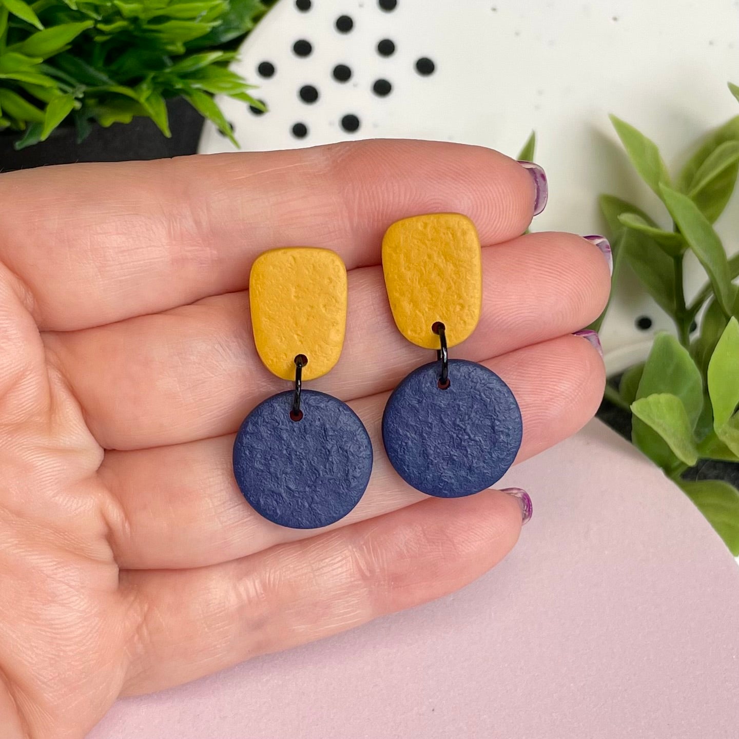 Mustard Yellow & Navy Blue colour pop dangle earrings held in hand for size reference