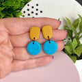 Mustard Yellow & Turquoise colour pop dangle earrings held in hand for size reference
