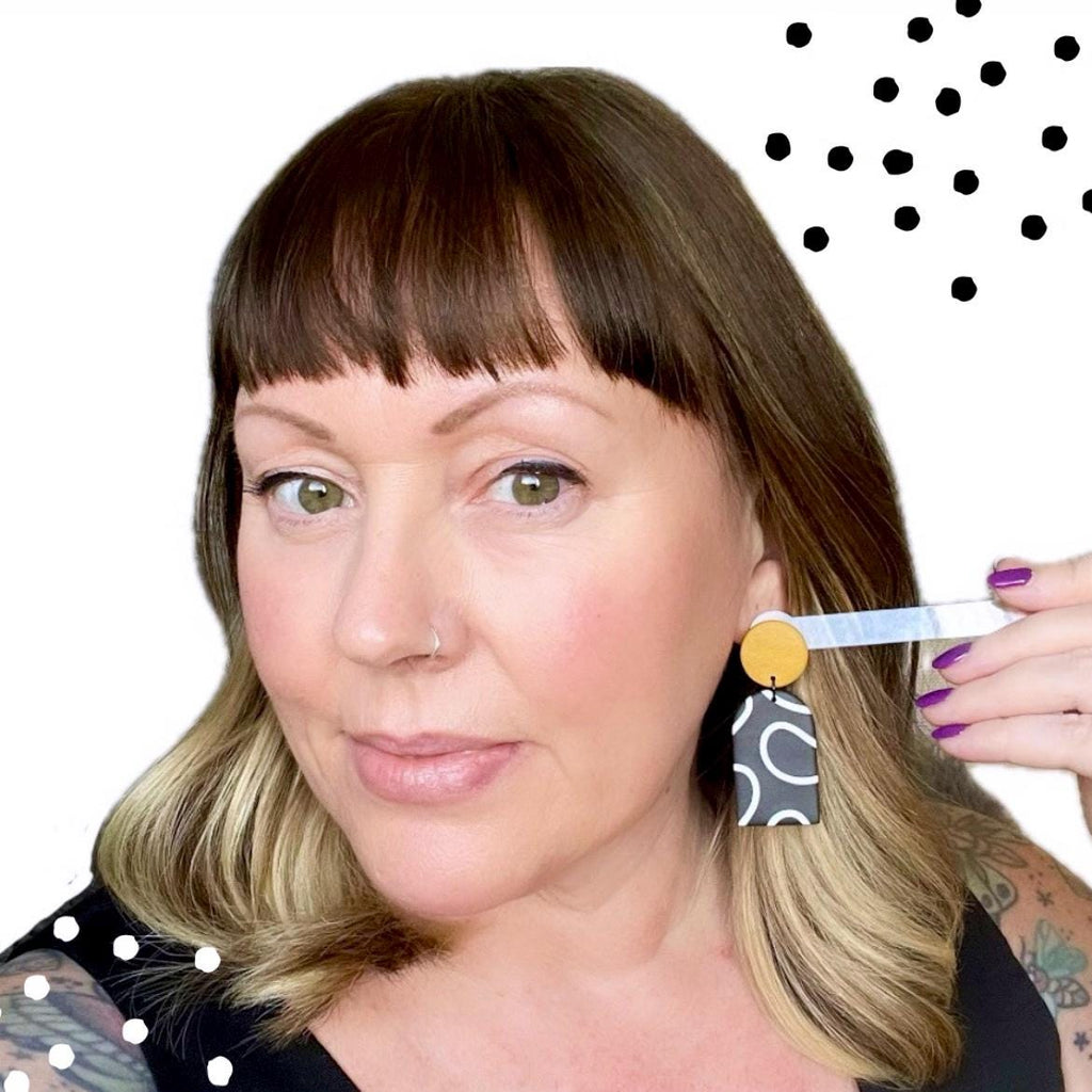 Try on picture of Kerry from Kay Jay Clay wearing the monochrome squiggle dangle earrings with yellow tops for size reference