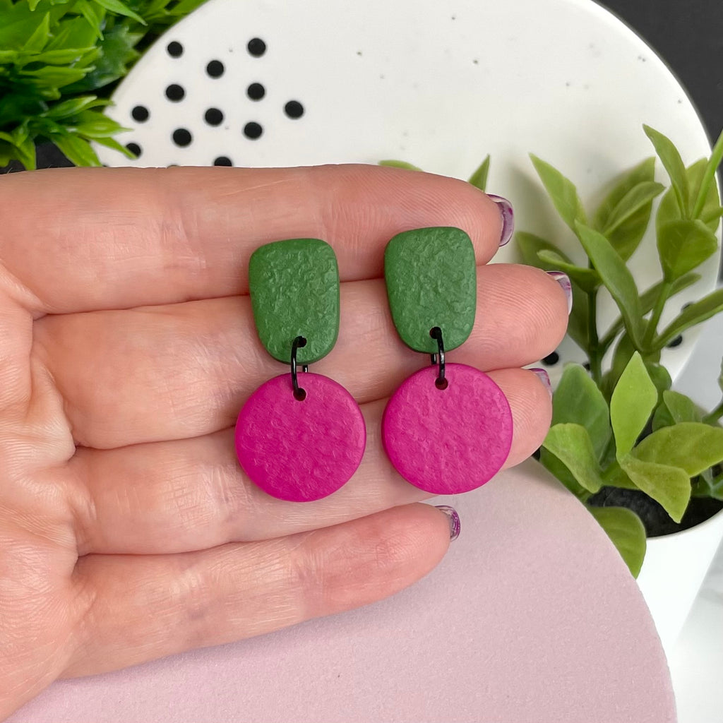 Olive Green & Hot Pink colour pop dangle earrings held in hand for size reference