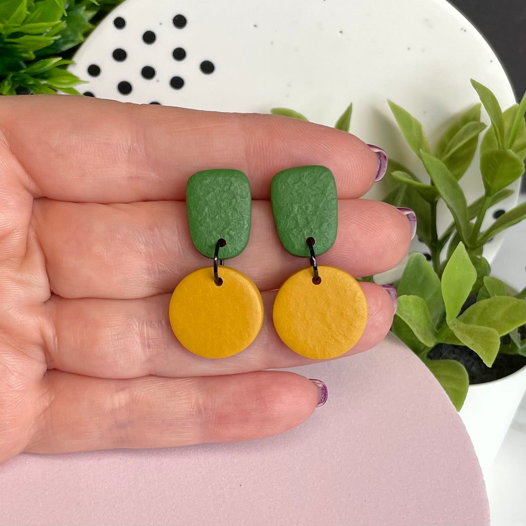 Olive Green & Mustard Yellow colour pop dangle earrings held in hand for size reference