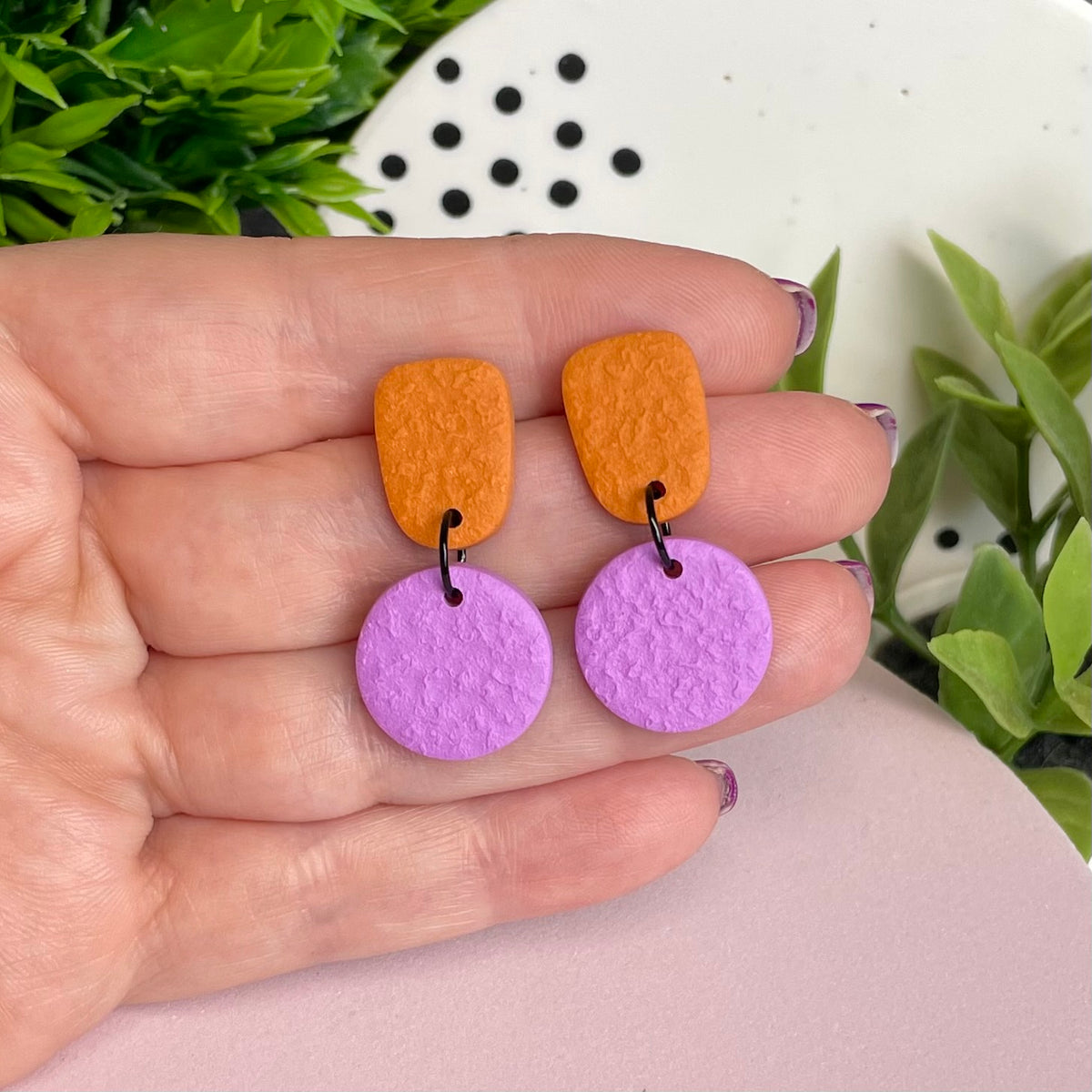 Orange & Lilac colour pop dangle earrings held in hand for size reference