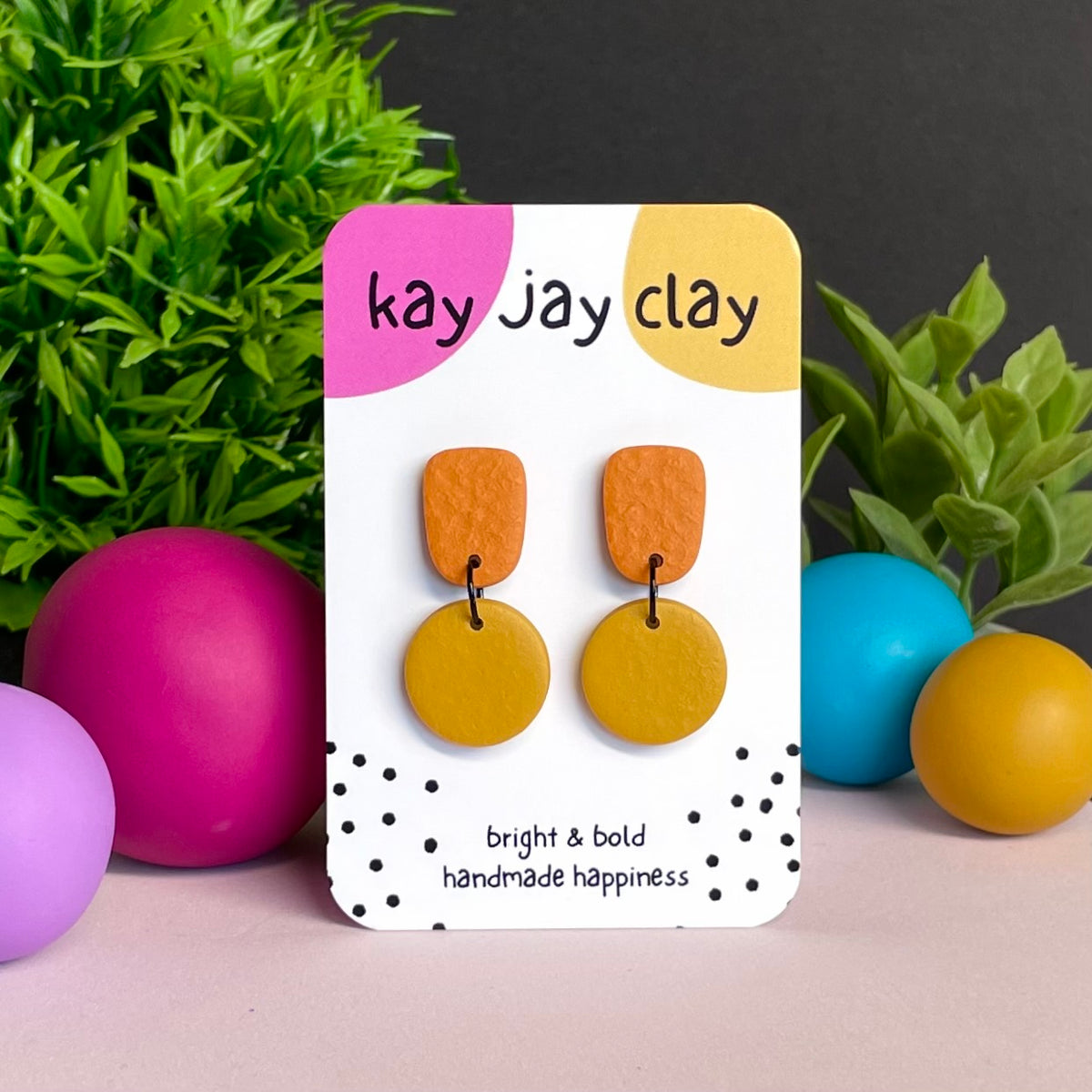 Orange & Mustard Yellow colour pop dangle earrings on Kay Jay Clay branded mounting card