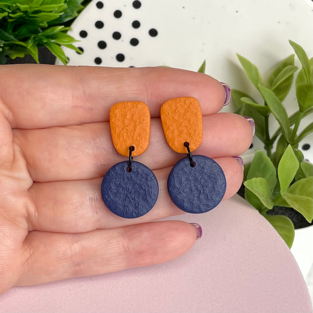 Orange & Navy Blue colour pop dangle earrings held in hand for size reference
