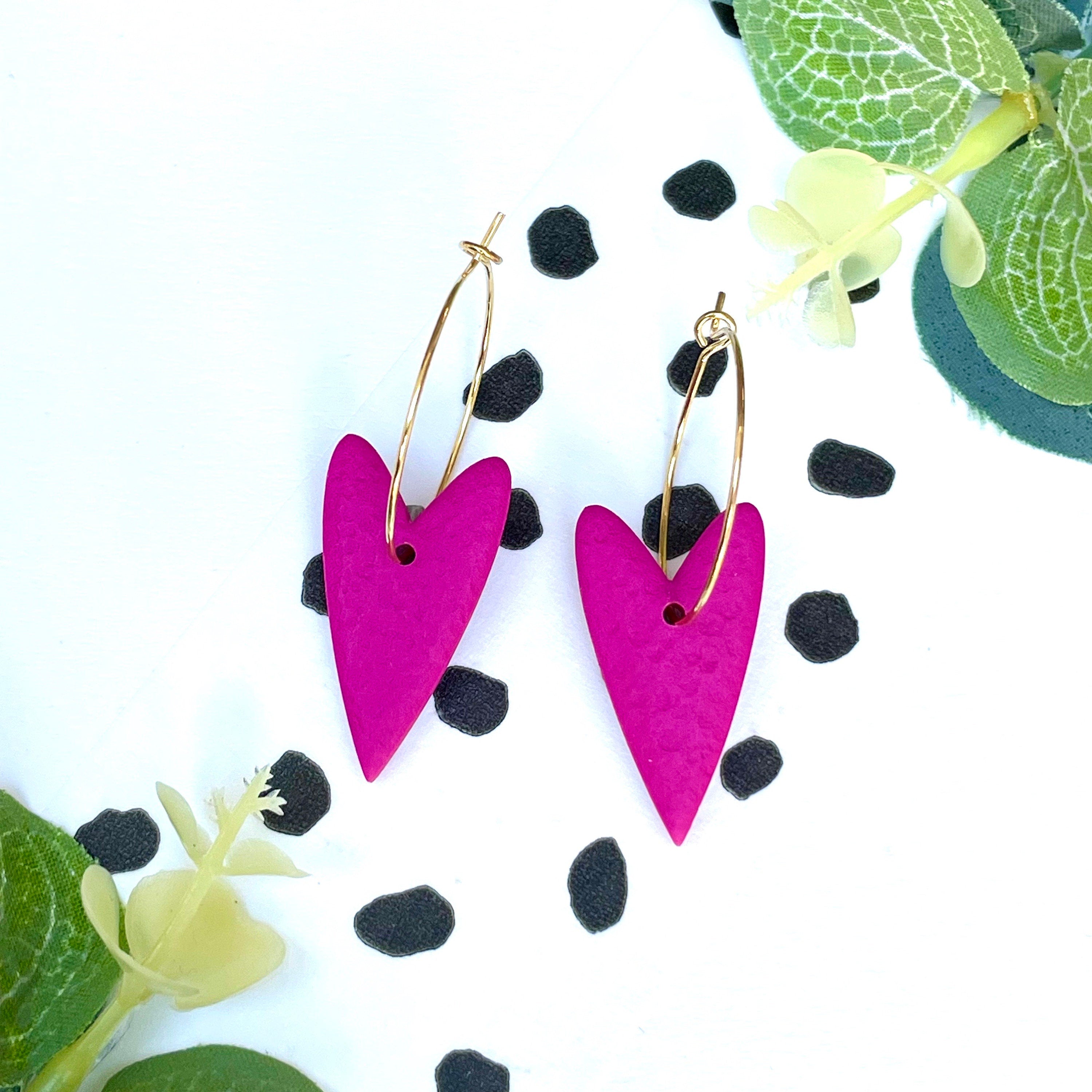 Hot pink heart-shaped earrings on a gold colour hoop