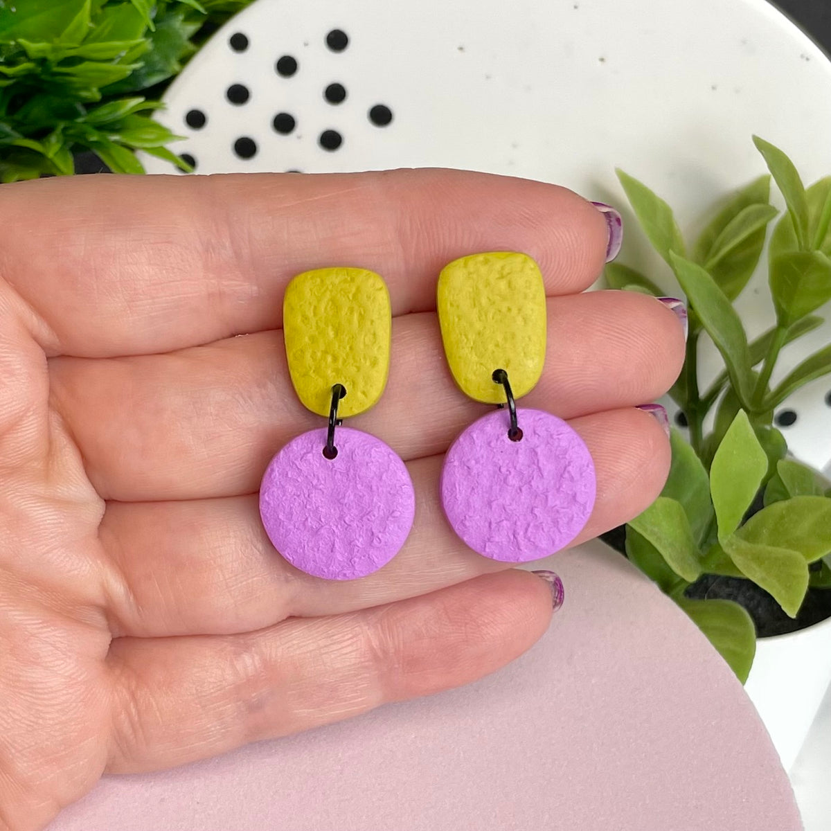 Pistachio Green & Lilac colour pop dangle earrings held in hand for size reference