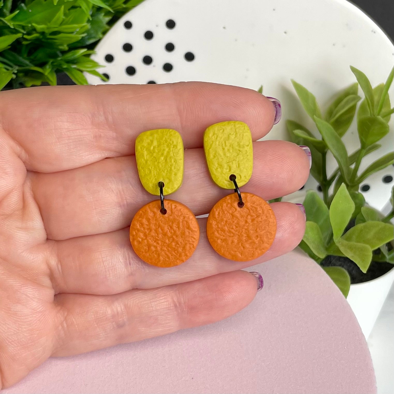 Pistachio Green & Orange colour pop dangle earrings held in hand for size reference