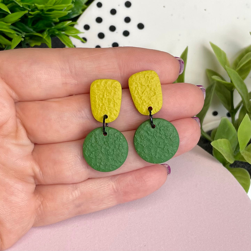 Pistachio & Olive Green colour pop dangle earrings held in hand for size reference