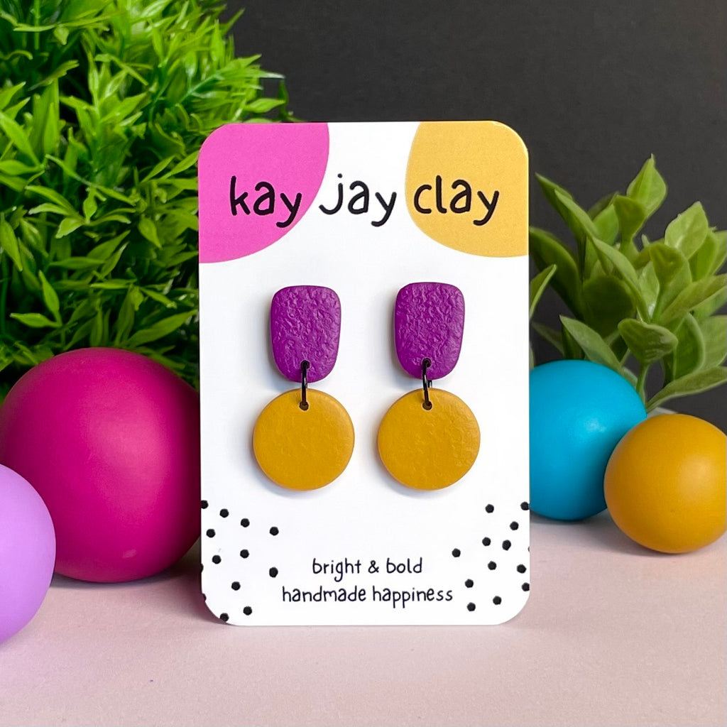 Purple & Mustard Yellow colour pop dangle earrings on Kay Jay Clay branded mounting card