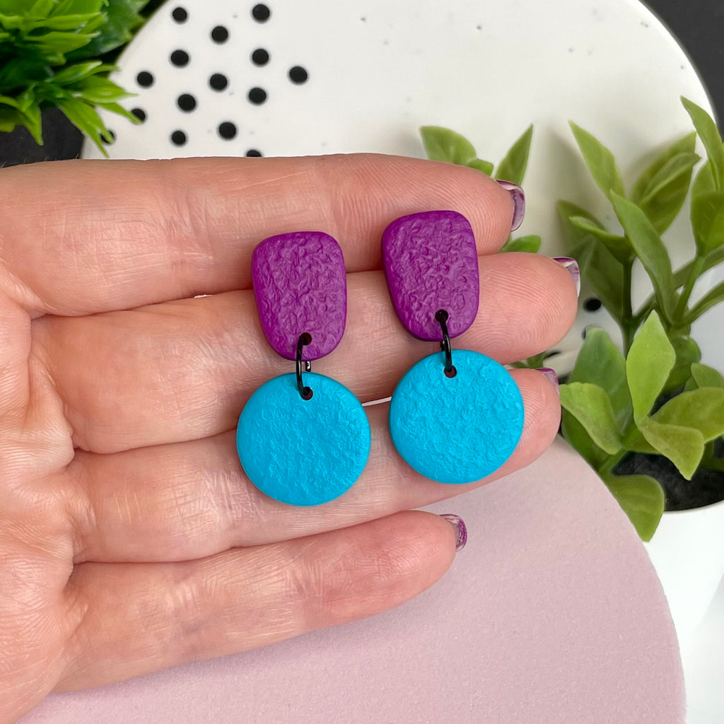 Purple & Turquoise colour pop dangle earrings held in hand for size reference