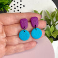 Purple & Turquoise colour pop dangle earrings held in hand for size reference