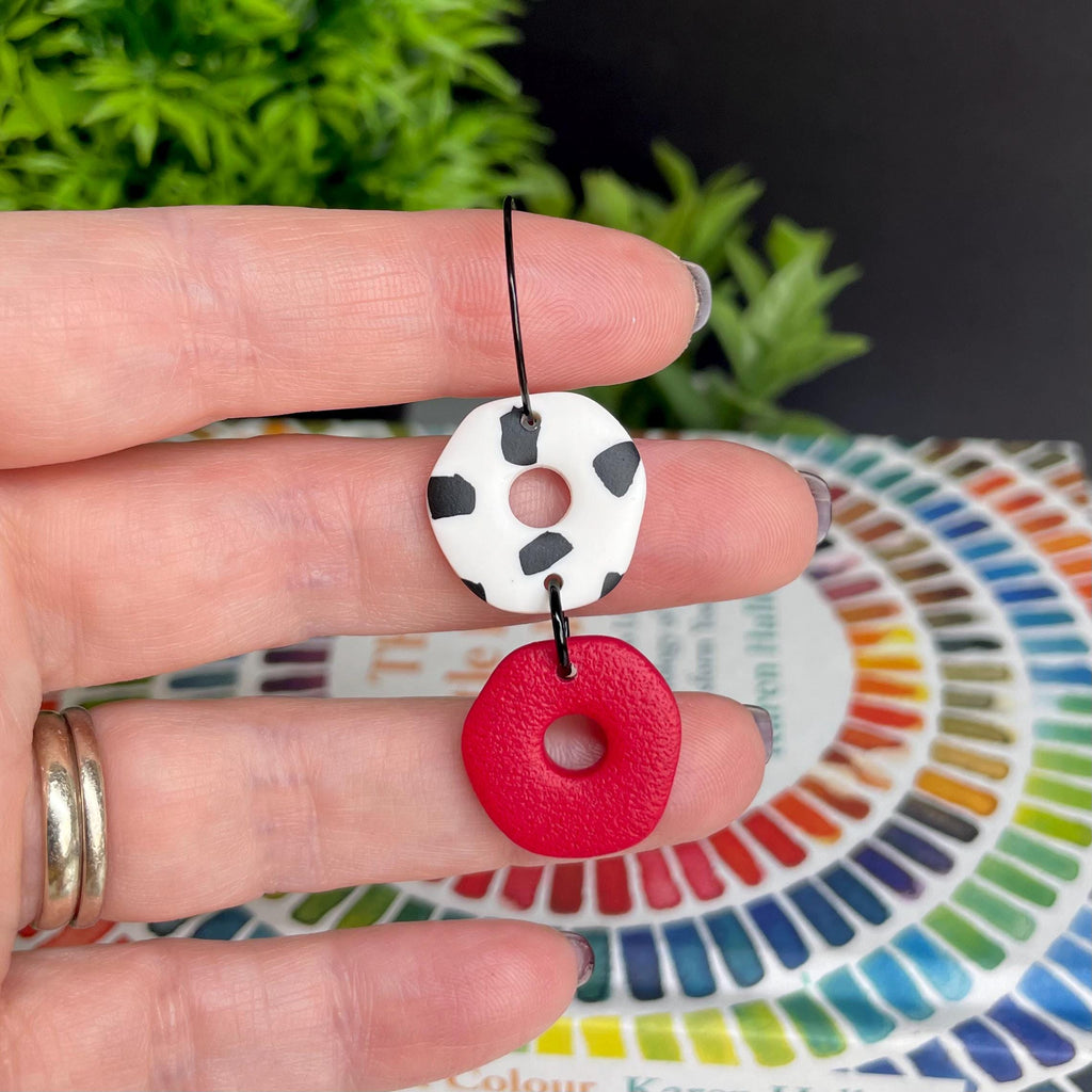 Hand holding a Red & Dalmatian print hoop earring