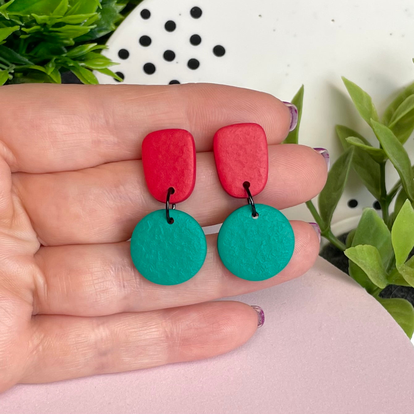Red & Emerald Green colour pop dangle earrings held in hand for size reference