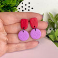 Red & Lilac colour pop dangle earrings held in hand for size reference