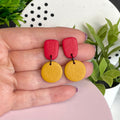Red & Mustard Yellow colour pop dangle earrings held in hand for size reference