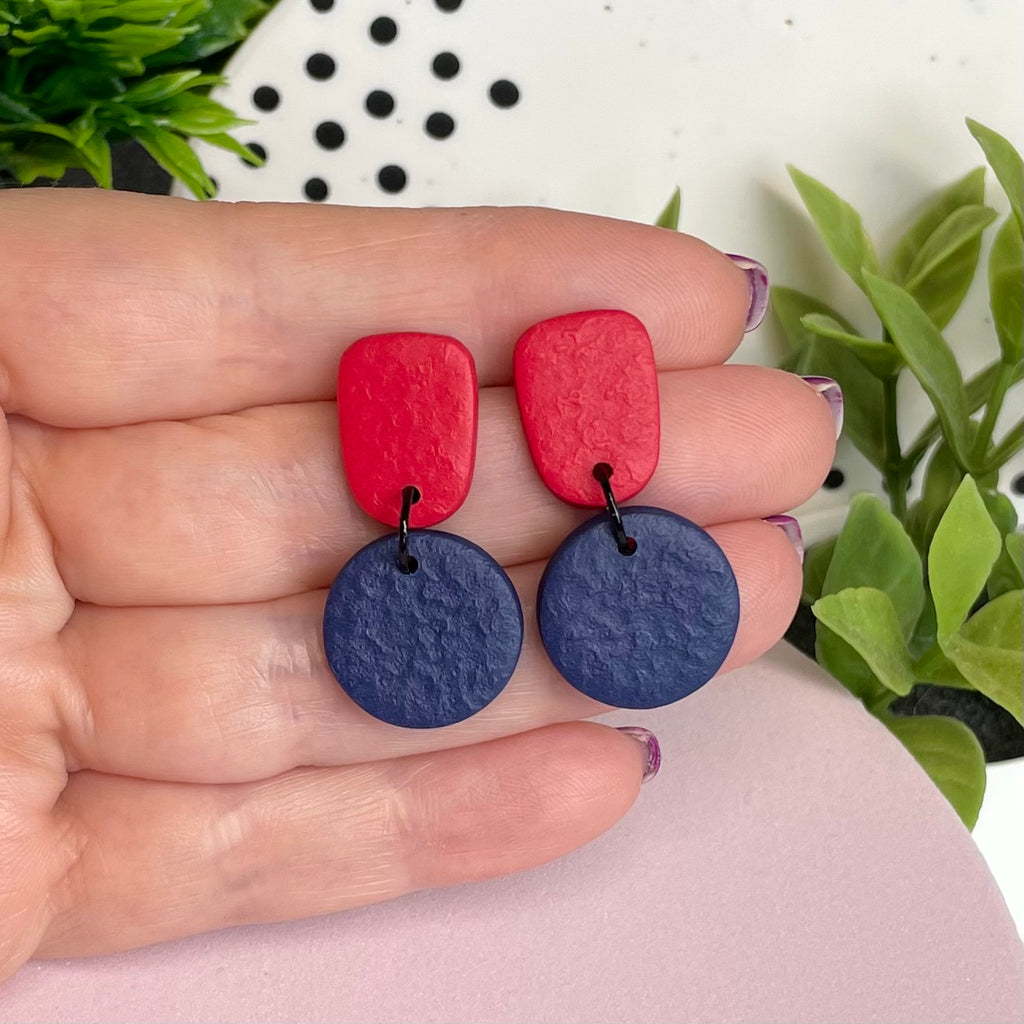 Red & Navy Blue colour pop dangle earrings held in hand for size reference