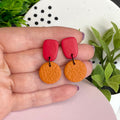 Red & Orange colour pop dangle earrings held in hand for size reference