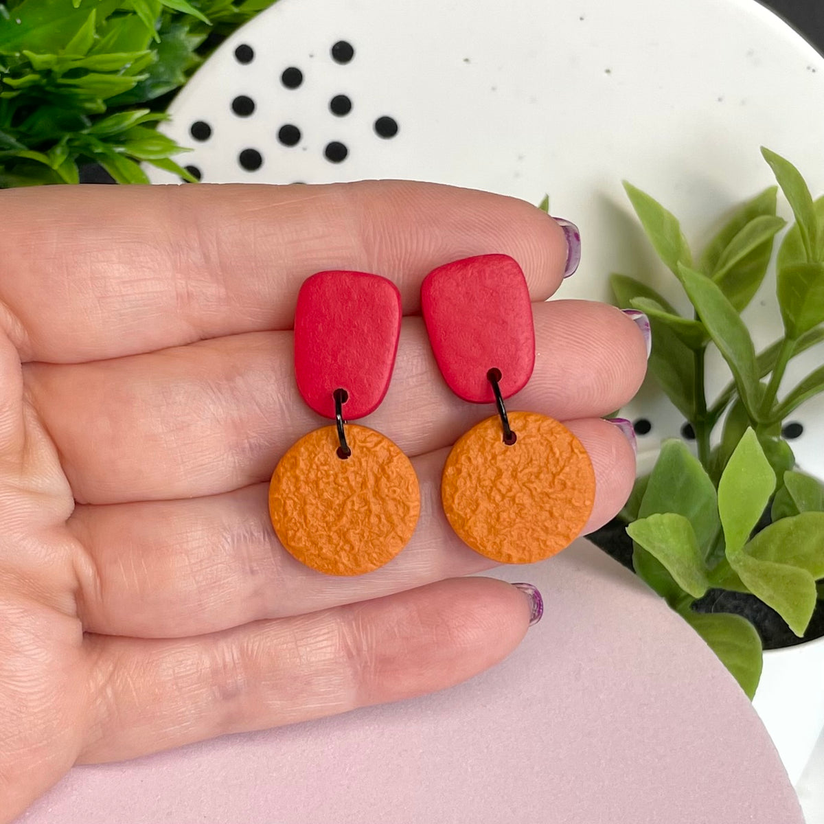 Red & Orange colour pop dangle earrings held in hand for size reference