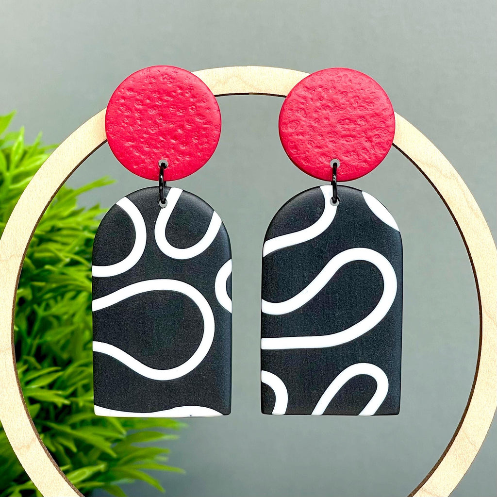 Black and white squiggle patterned earrings with red tops 