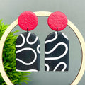 Black and white squiggle patterned earrings with red tops 