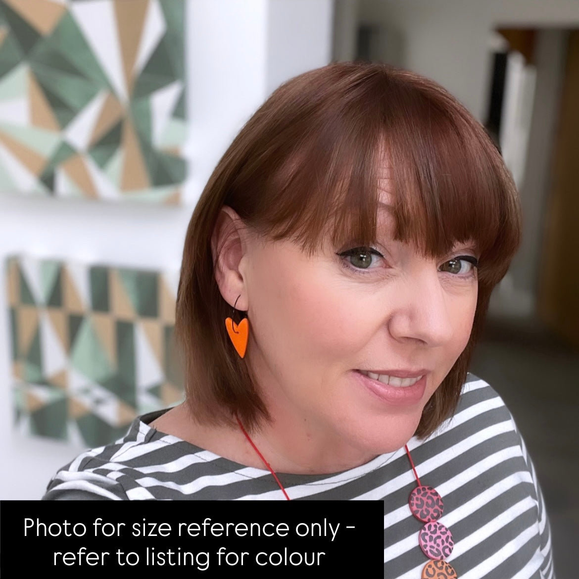 Kerry from Kay Jay Clay wearing the orange heart hoop earrings to show the size for reference