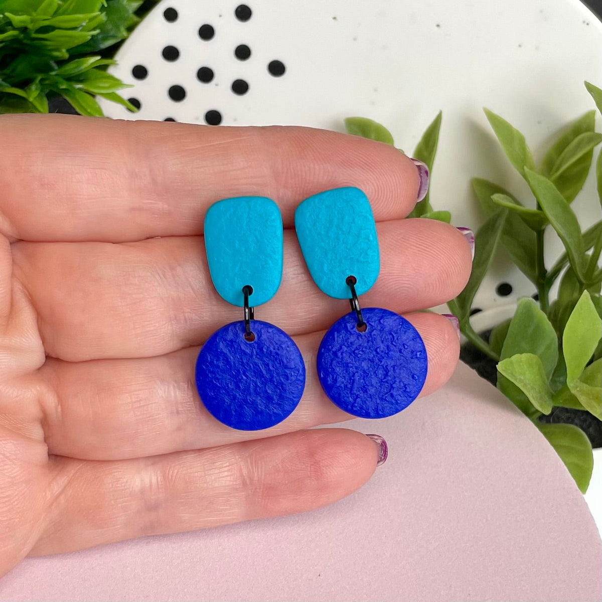 Turquoise & Electric Blue colour pop dangle earrings held in hand for size reference