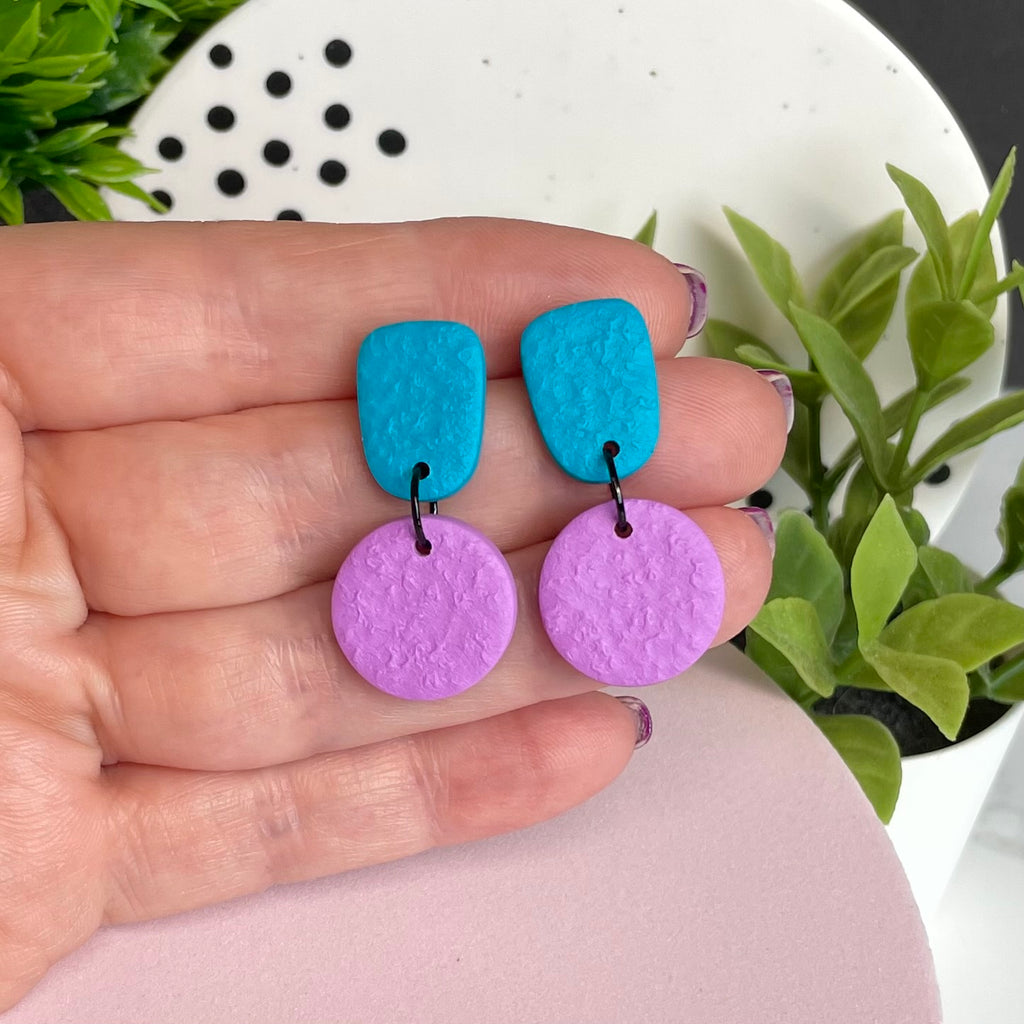 Turquoise & Lilac colour pop dangle earrings held in hand for size reference