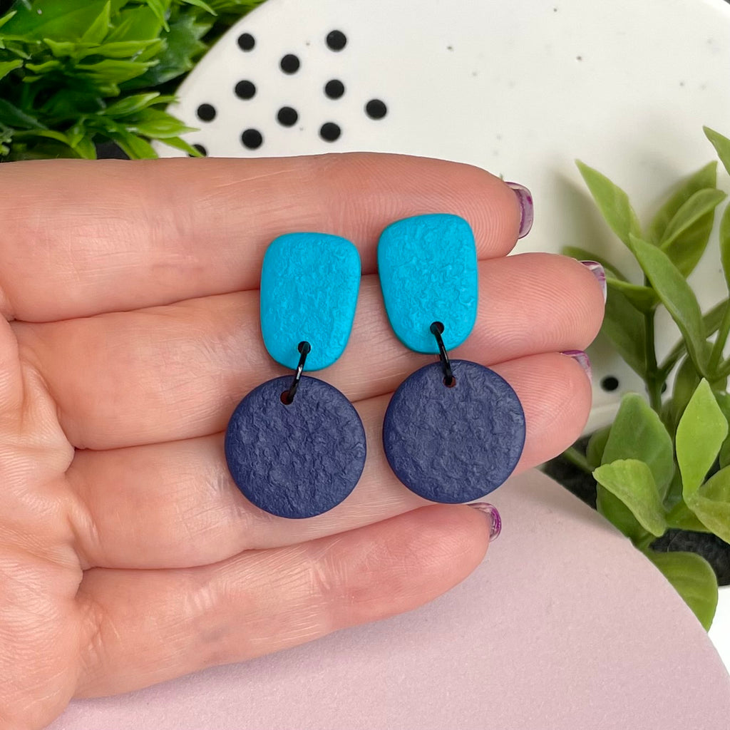 Turquoise & Navy Blue colour pop dangle earrings held in hand for size reference