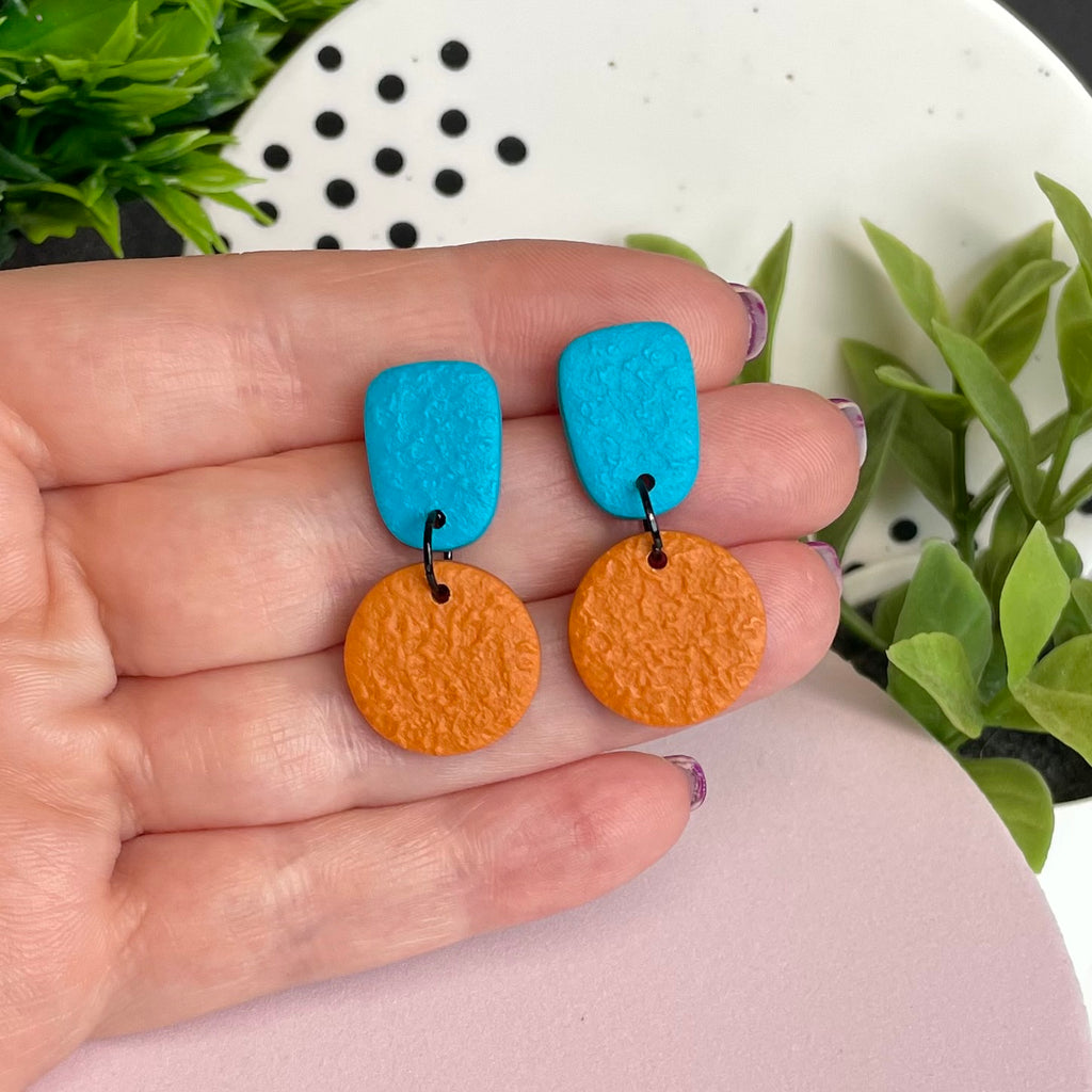 Turquoise & Orange colour pop dangle earrings held in hand for size reference