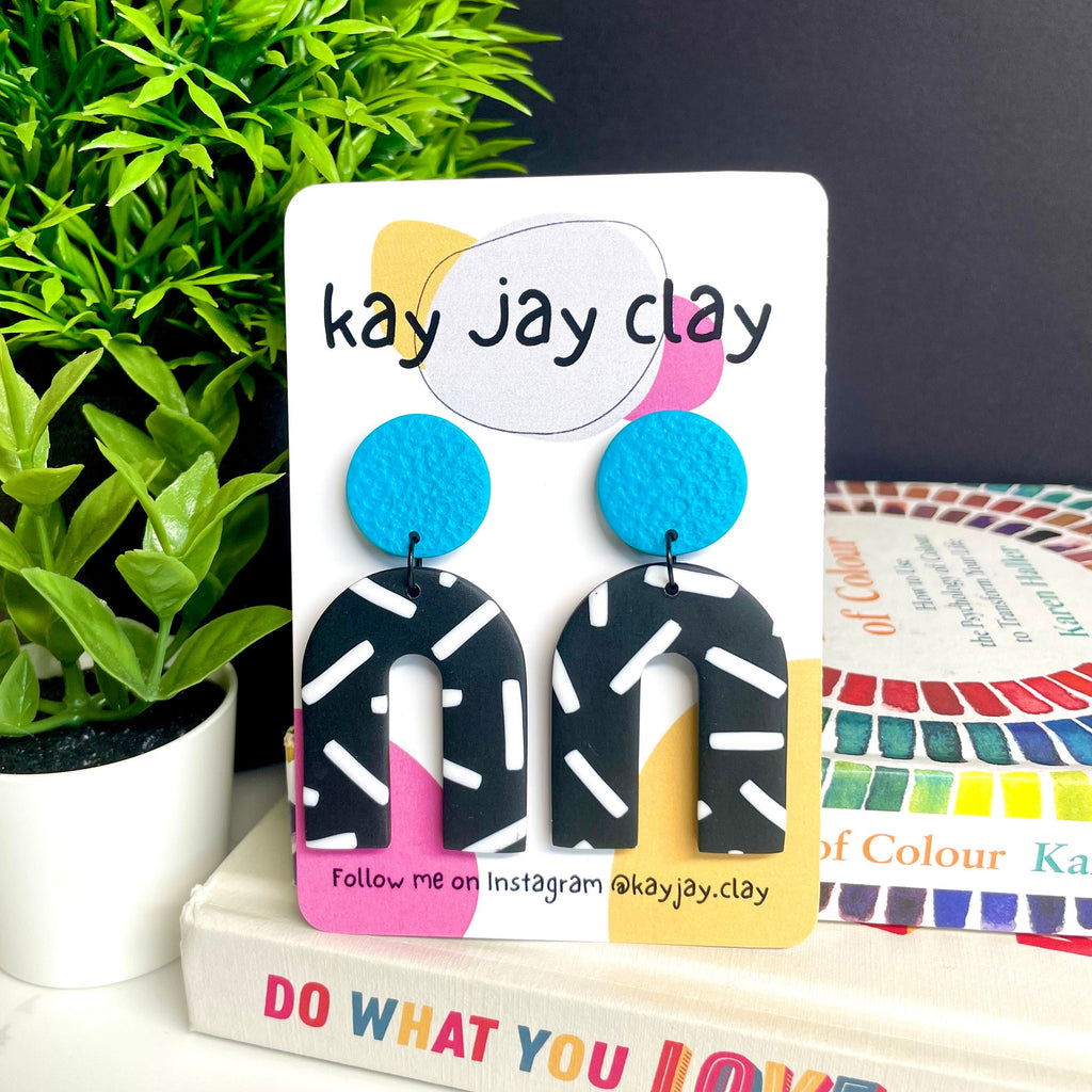 Turquoise and monochrome sprinkles arch dangle earrings on a Kay Jay Clay mounting card