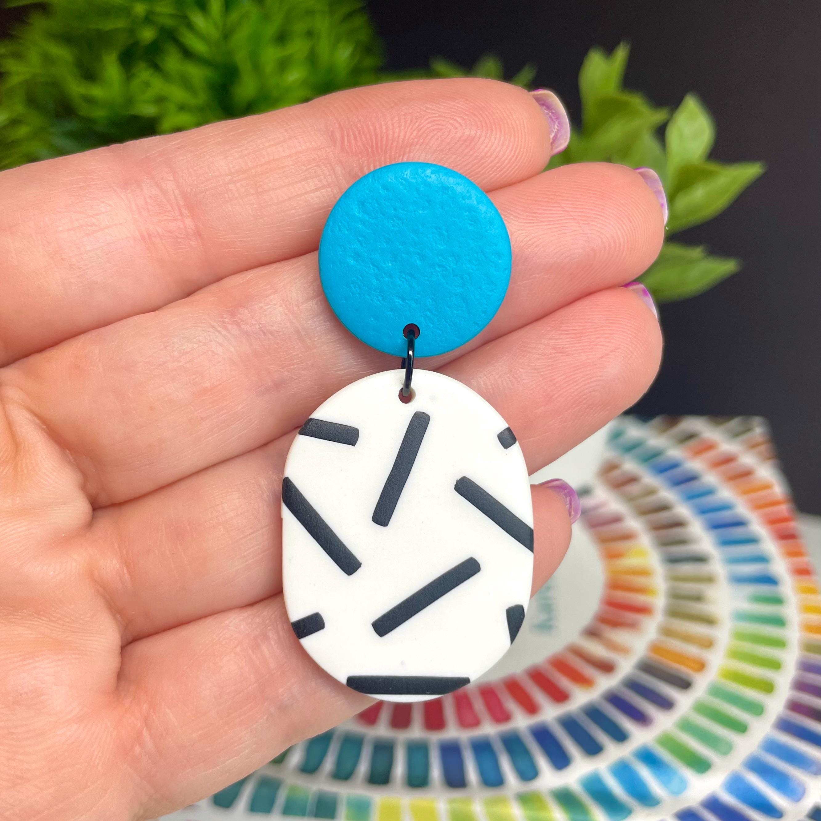 Hand holding  the turquoise top mono sprinkle oval earrings with a colour swatch in the background