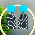 Black and white squiggle patterned earrings with turquoise circular tops